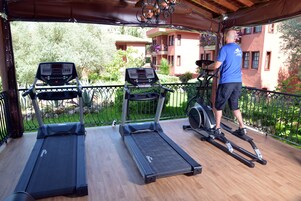 Een overdekt buitengebied met twee loopbanden en een hometrainer.