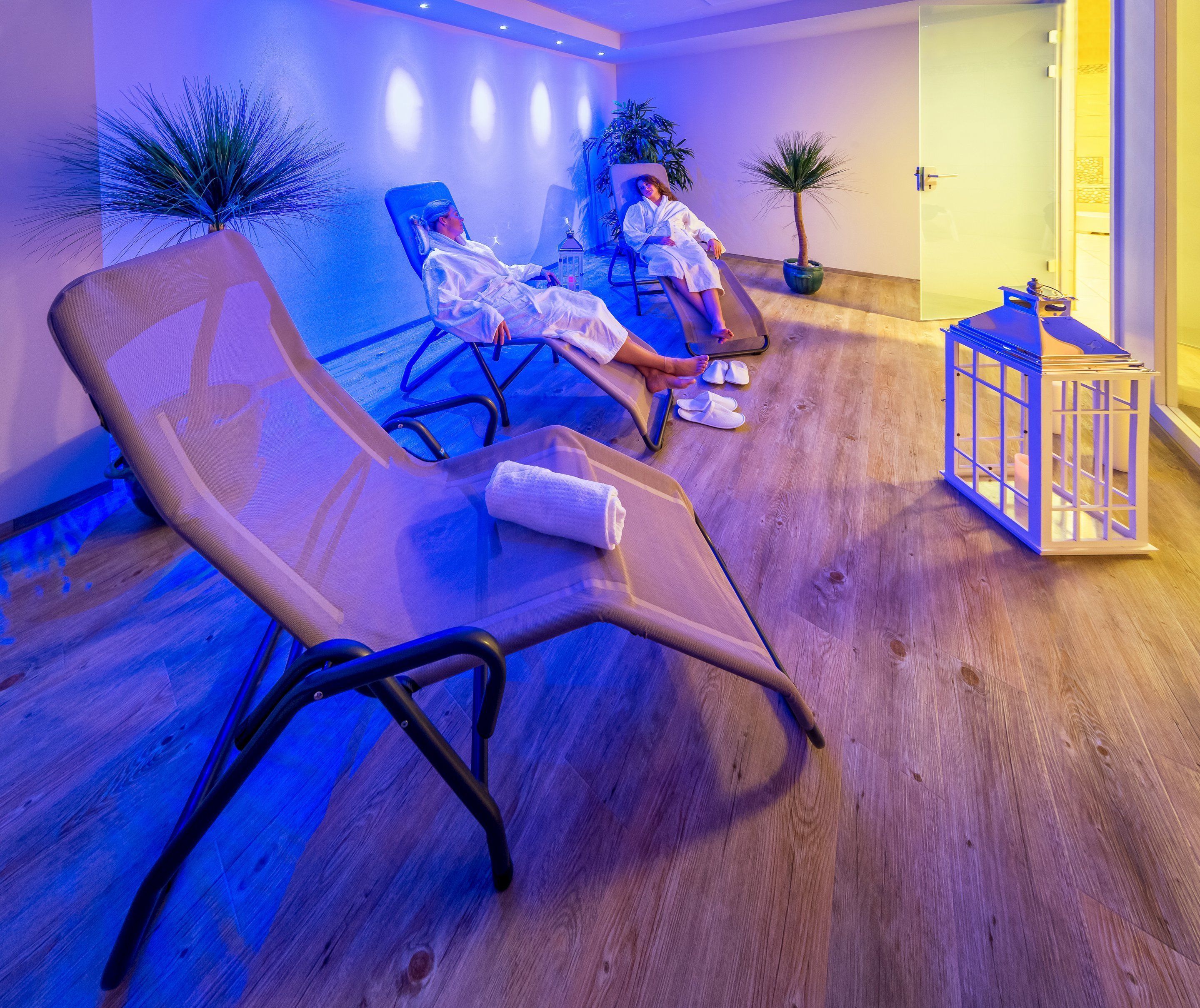 Um quarto com duas poltronas reclináveis, uma mesinha e um vaso de planta.