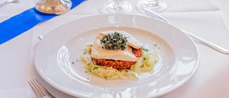 A plate of food with a white base, topped with a creamy sauce and a garnish of microgreens.