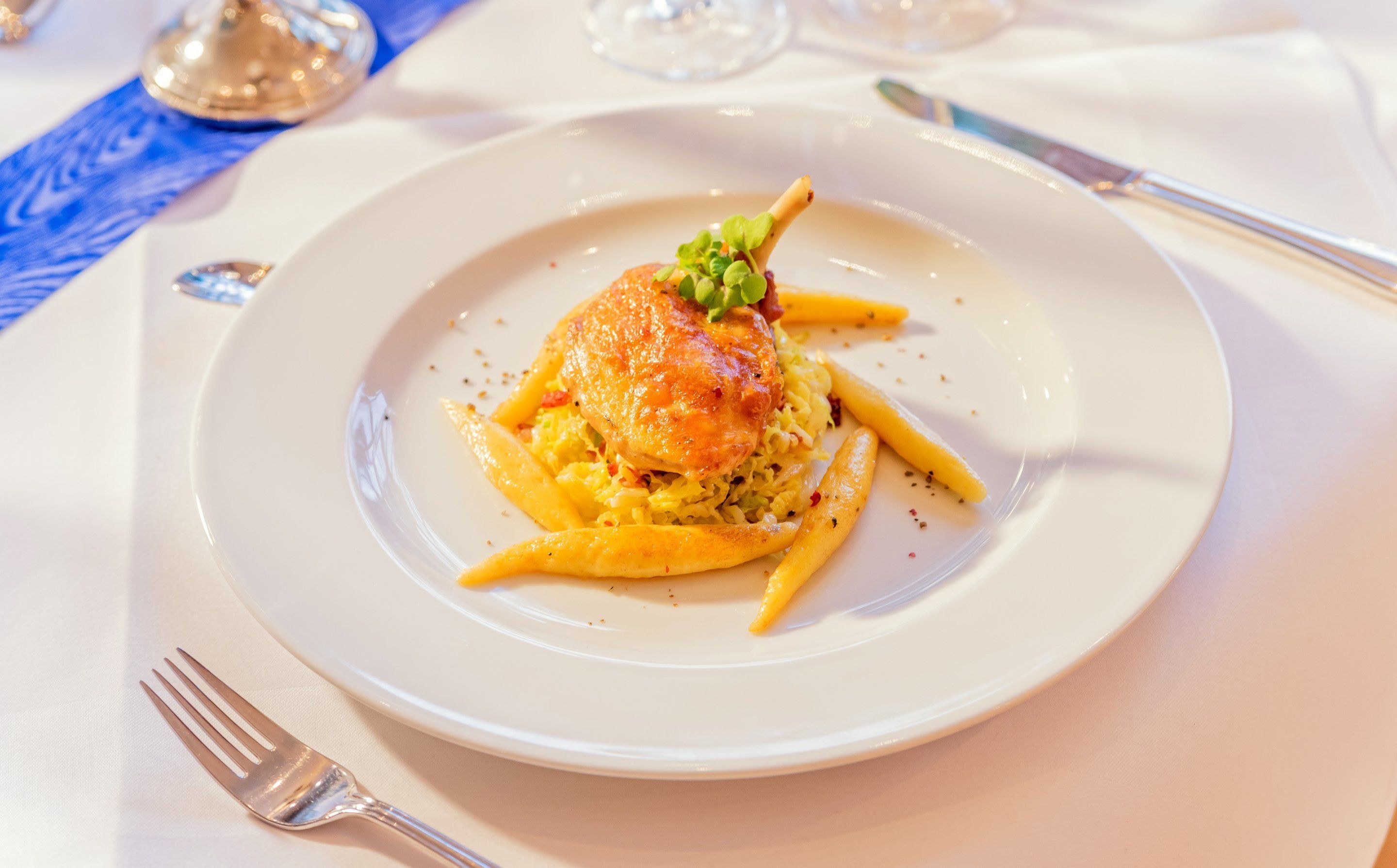 Ein Teller mit Essen, bestehend aus einer goldbraunen Pattie, grüner Dekoration und gelben Nudeln.