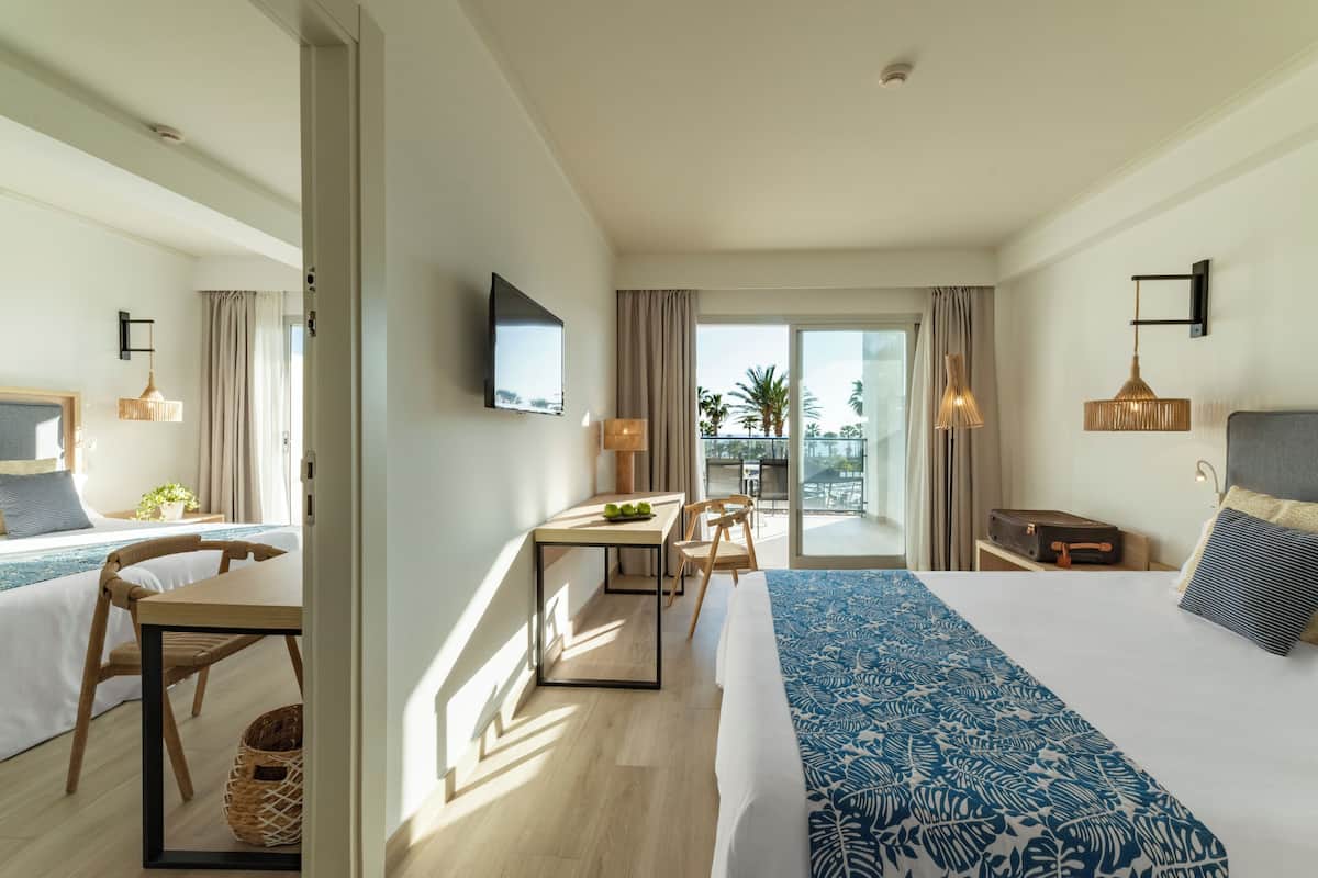 Ein Hotelzimmer mit einem großen Bett, einem Schreibtisch und einem Balkon mit Blick.