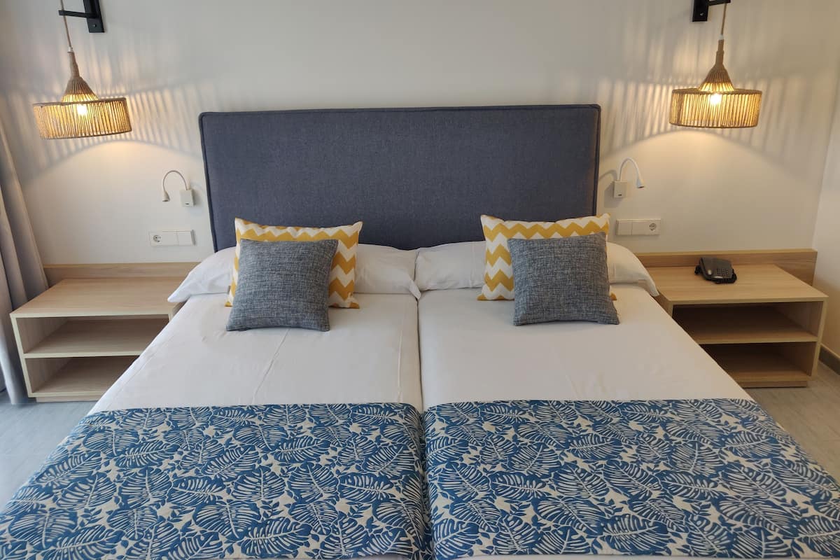 Ein Doppelbett mit zwei Kissen, ein Nachttisch und eine Wandleuchte.