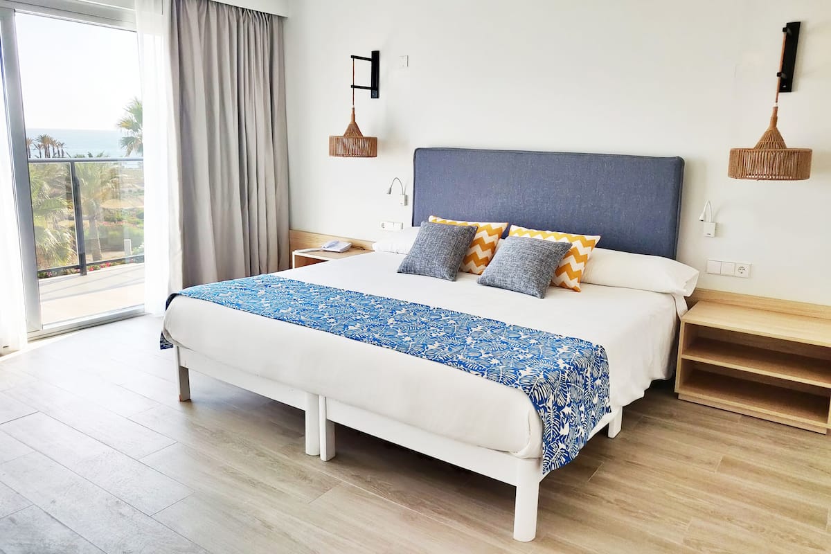 Ein modernes Hotelzimmer mit einem großen Bett, Blick ins Freie und einem Balkon.