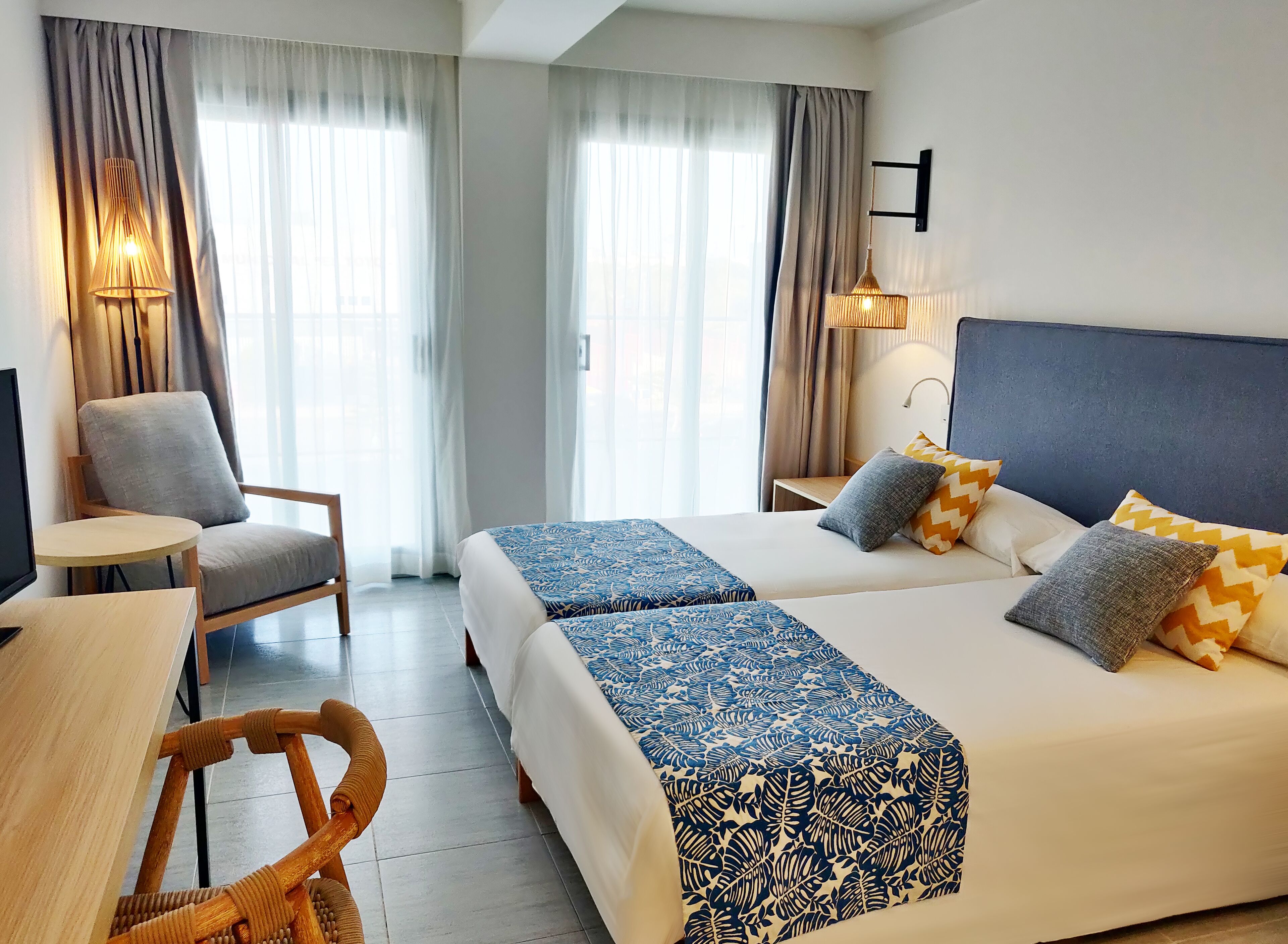 Une chambre d’hôtel avec deux lits, une chaise, une petite table et un téléviseur.