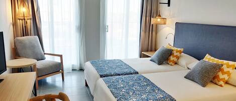 Une chambre d’hôtel avec deux lits, une chaise, une petite table et un téléviseur.