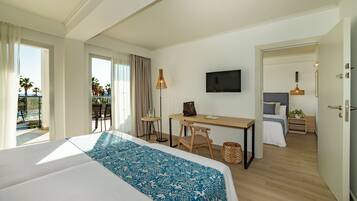 A hotel room with a large bed, a desk, a chair, a TV, and a balcony with a pool view.