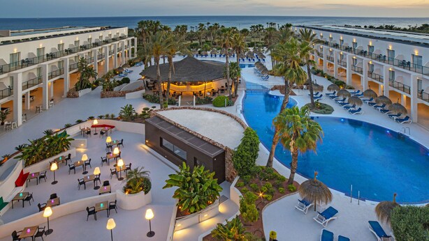 Un resort con piscina, mobiliario exterior y vista al océano.