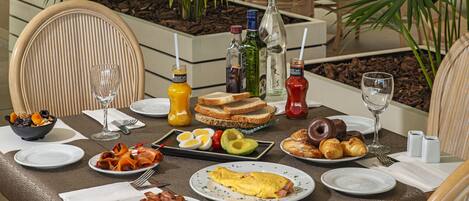A breakfast table with various food items, drinks, and condiments.