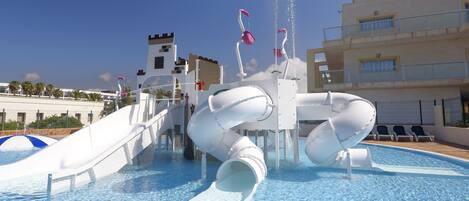 A water park with a large pool, slides, and a castle-like structure in the background.