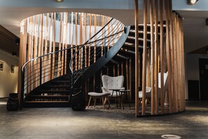 Stunning spiral staircase leads to a cozy lounge area with a comfortable chair and small table.