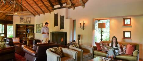 A spacious living room with a high ceiling, a fireplace, and a large window.