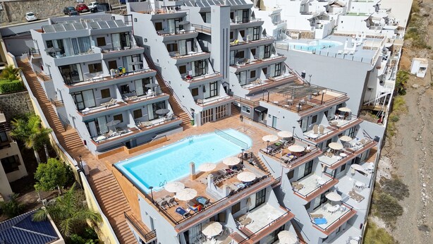 Un hôtel à plusieurs étages doté d’une piscine sur le toit, de balcons et offrant une vue sur le paysage environnant.