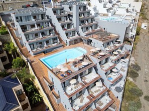 Un hôtel à plusieurs étages doté d’une piscine sur le toit, de balcons et offrant une vue sur le paysage environnant.