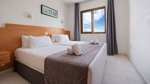 Une chambre d’hôtel avec un grand lit, une tête de lit en bois, une fenêtre avec des rideaux et un tableau encadré au mur.