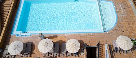 Una piscina rectangular con un bordeado de baldosas, equipada con una escalera y una plataforma de salto.