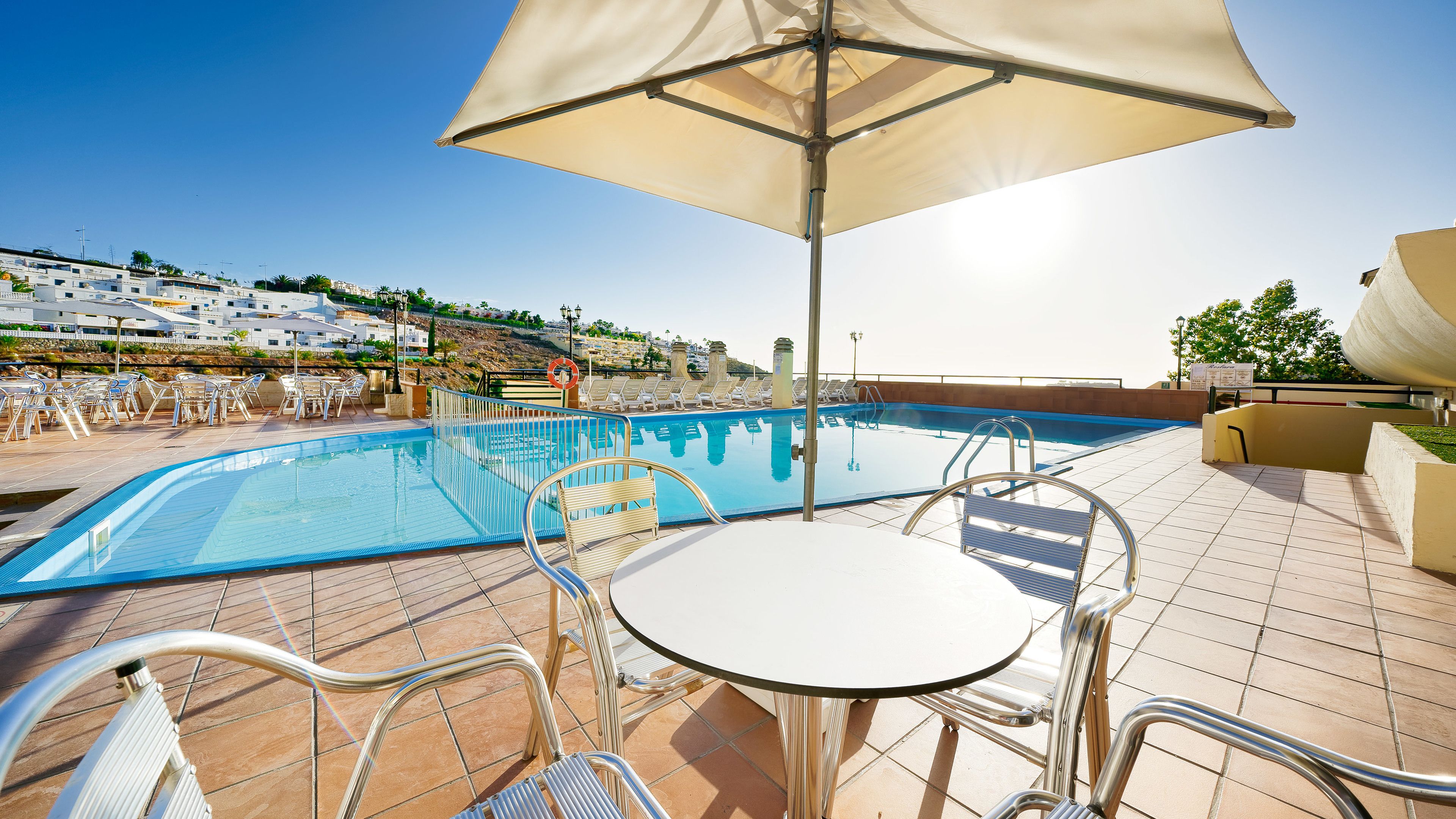 A poolside area with a pool, lounge chairs, and a table under a canopy.