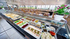 A buffet with various food items and a seating area with tables and chairs. - Ura Nido del Águila (Mogan)