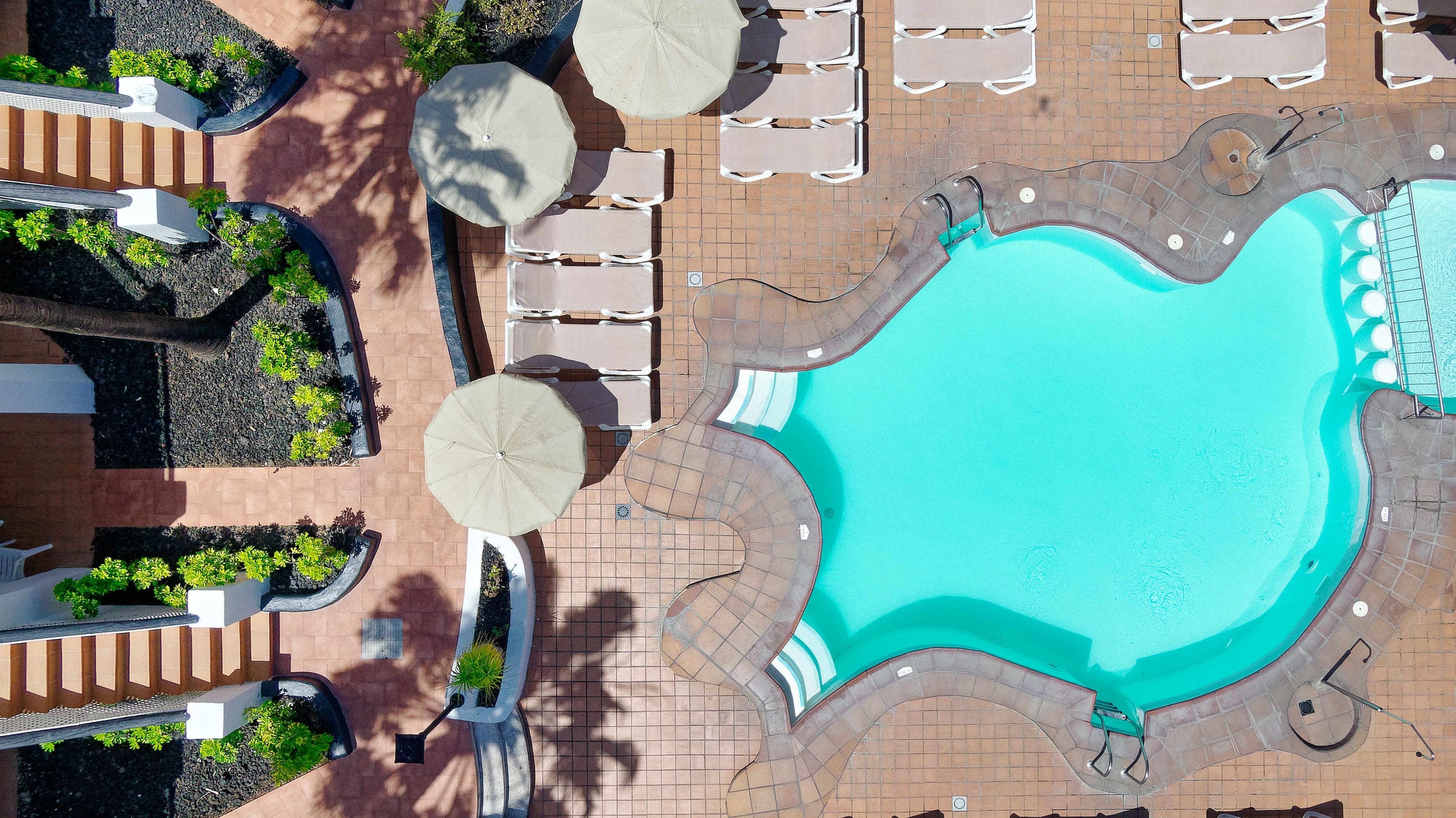 An aerial view of a pool area with lounge chairs and umbrellas.