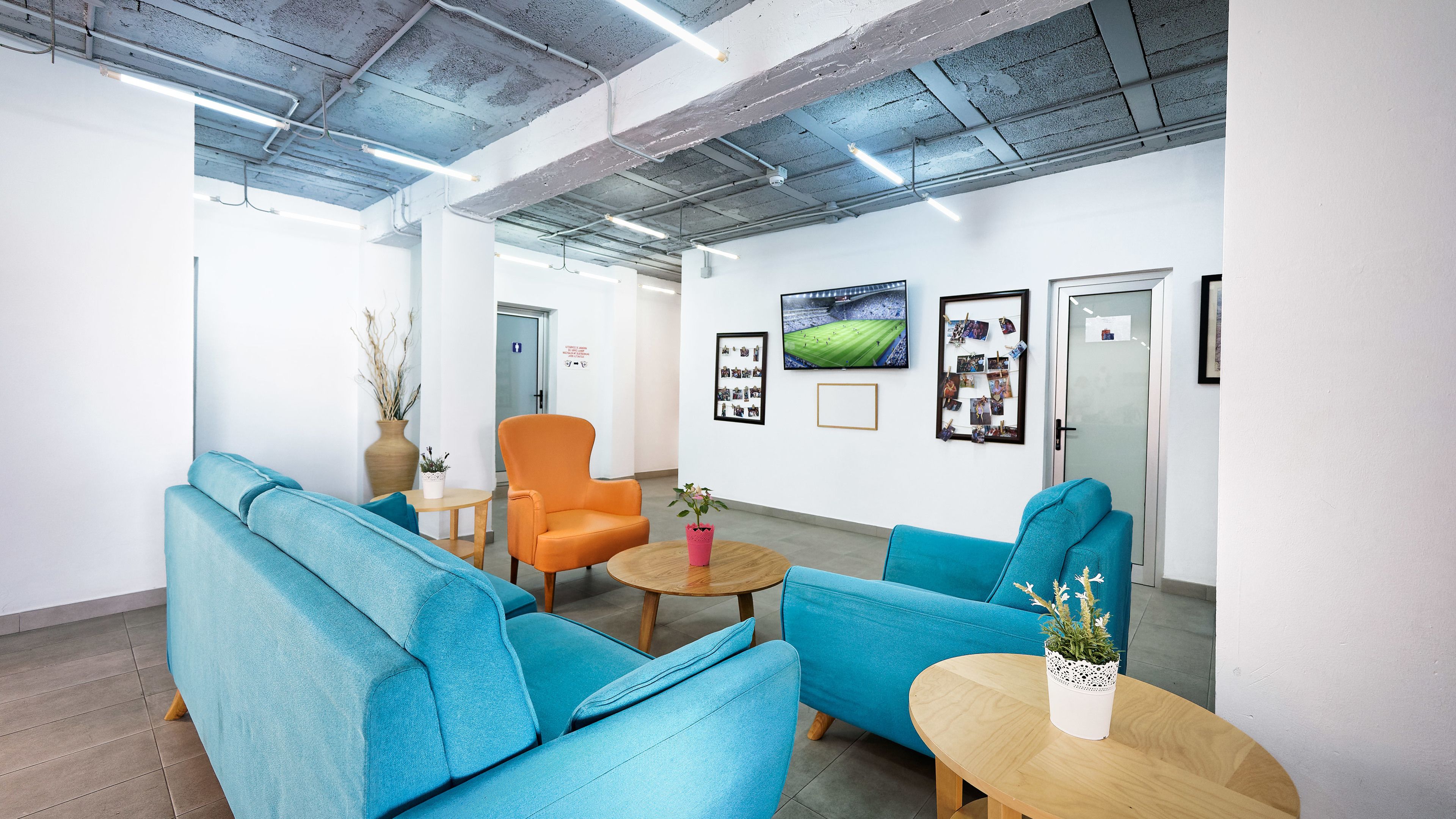 Un espace d’attente moderne avec des canapés bleus, une table basse en bois et un seul fauteuil orange.