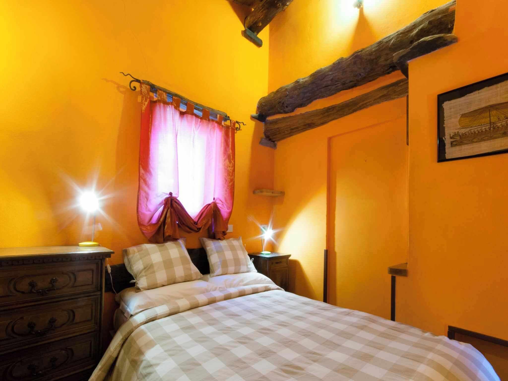 A cozy bedroom with a bed, two nightstands, a dresser, and a window with curtains.