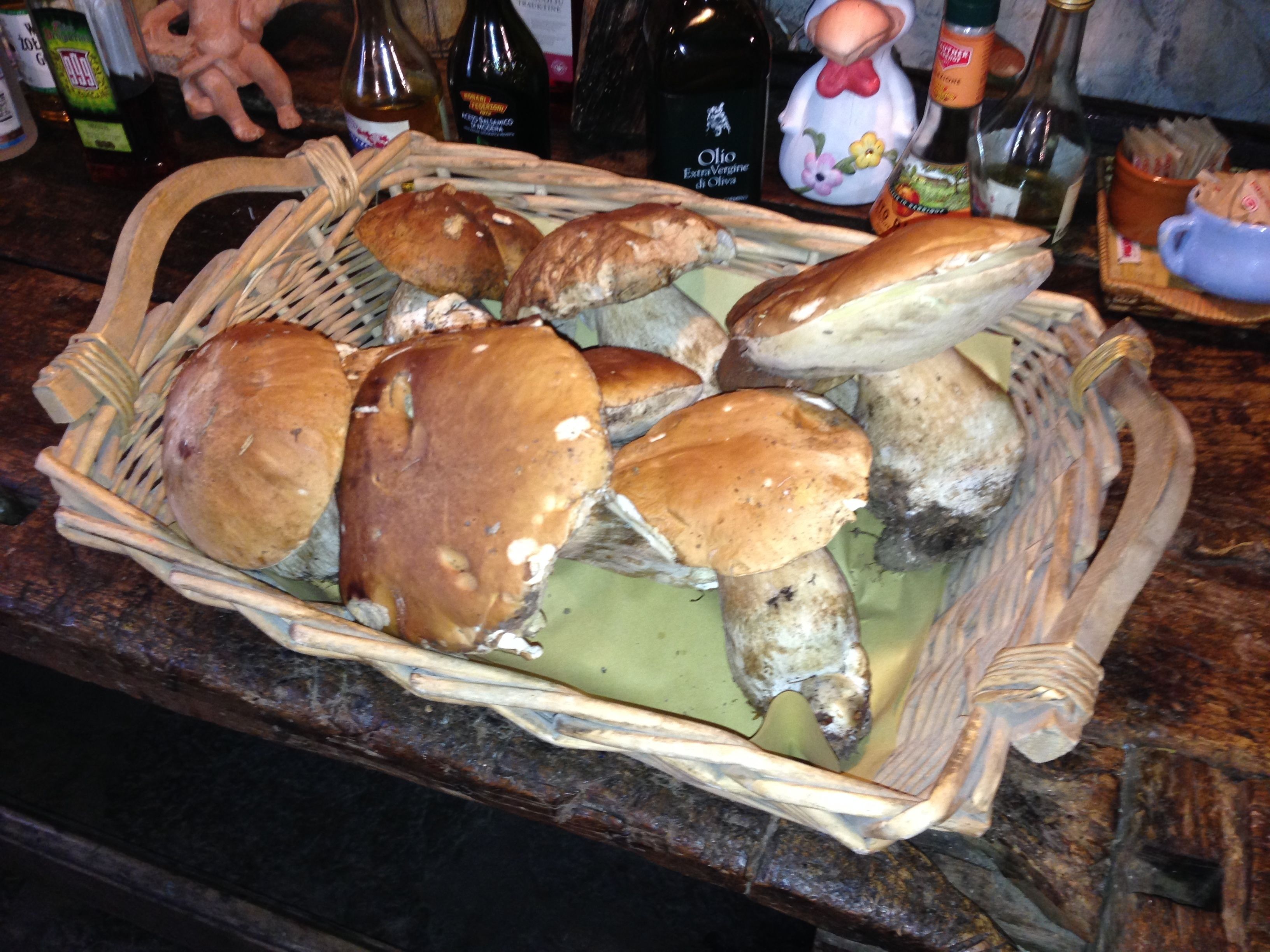 A wicker basket filled with bread rolls and a bottle of olive oil on a kitchen counter.
