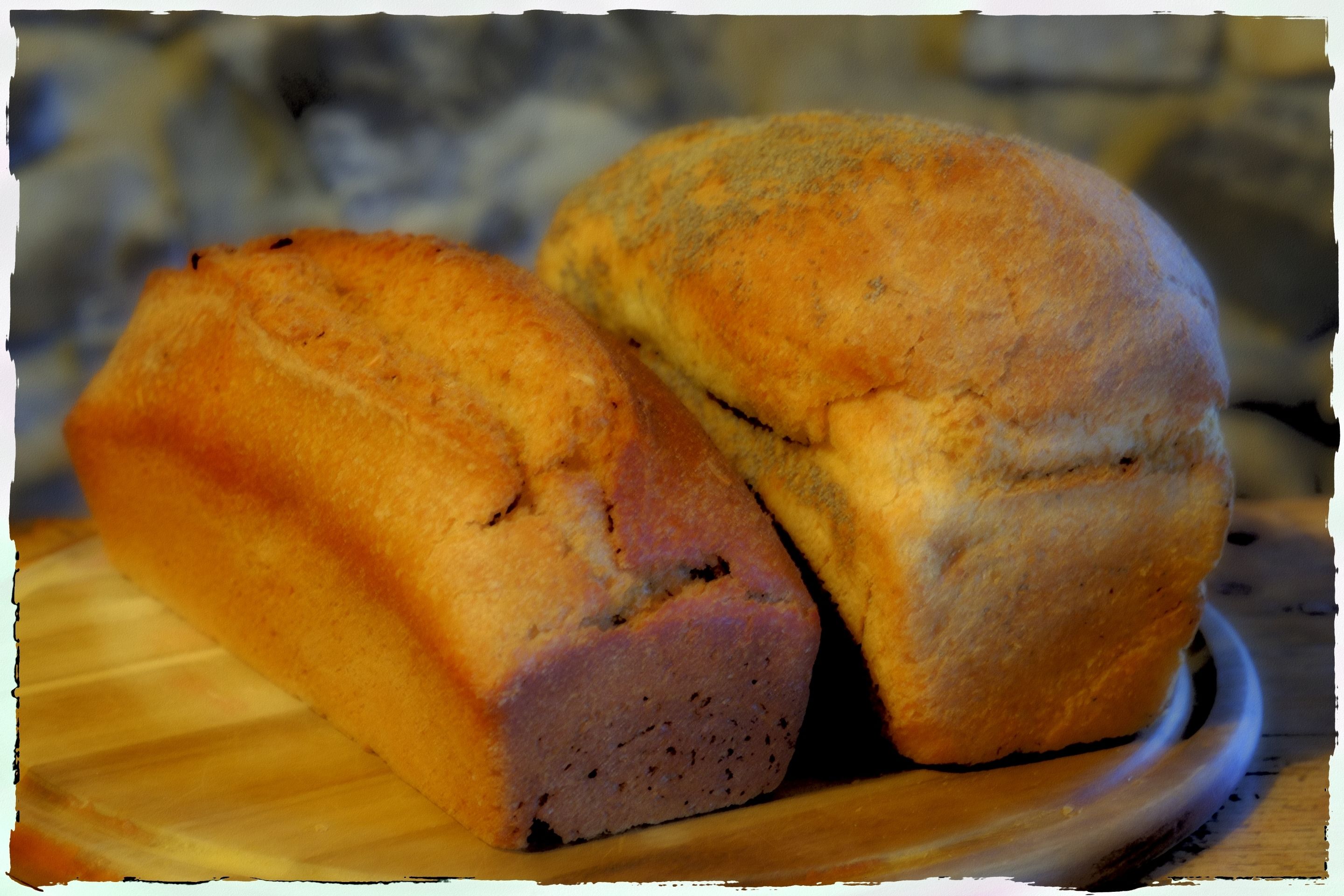 Two loaves of bread on a wooden cutting board.
