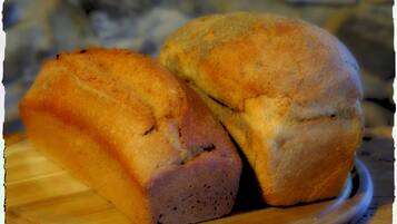 Two loaves of bread on a wooden cutting board.