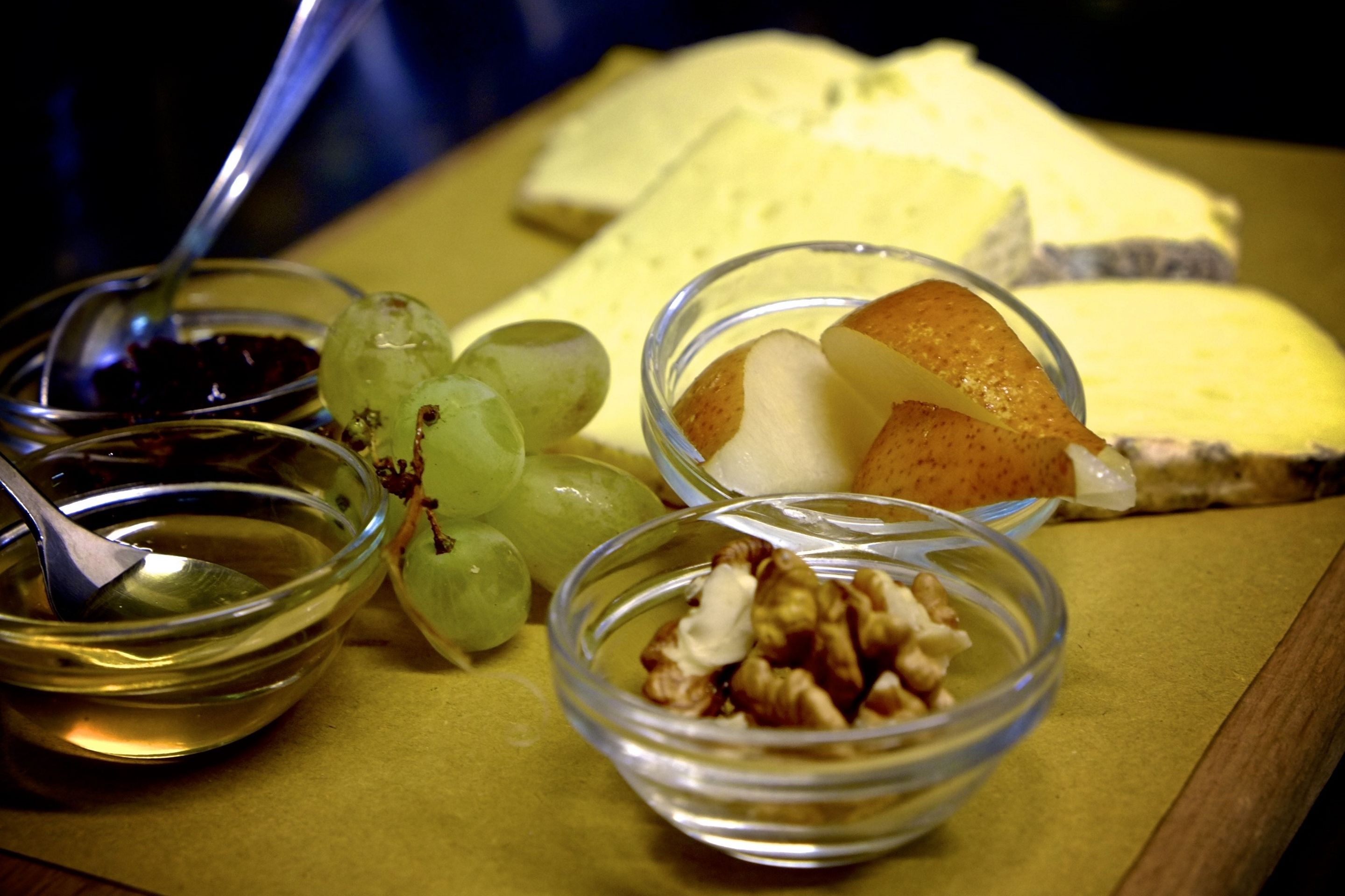 Una bandeja con queso, uvas, nueces y una cuchara.