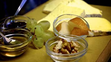Una bandeja con queso, uvas, nueces y una cuchara.