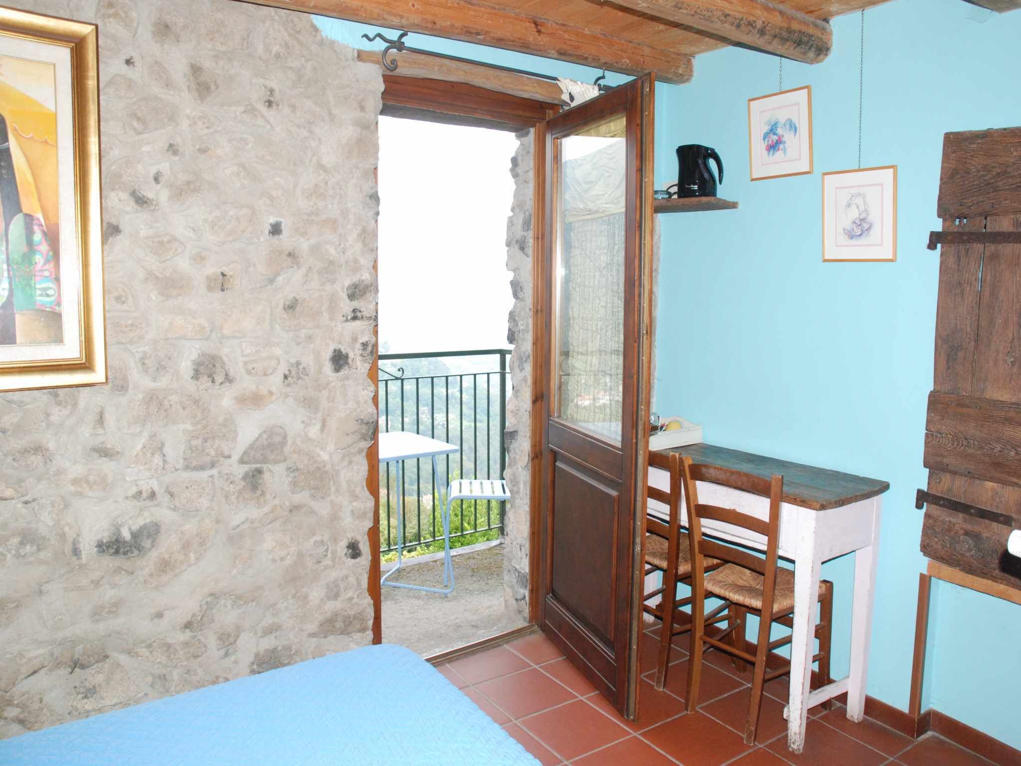 A small room with a bed, a desk with a chair, a window, and a balcony.