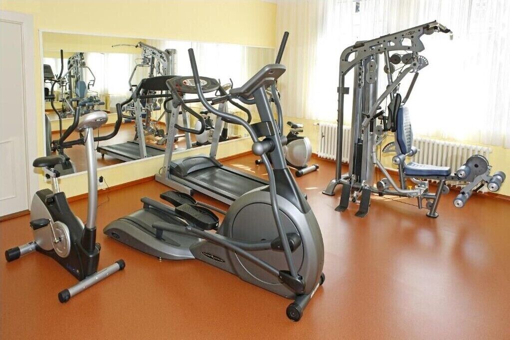 Un gimnasio con varios equipos de ejercicio, incluyendo cintas de correr, elípticas y máquinas de pesas.