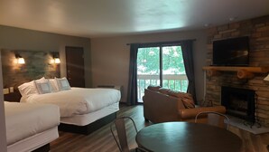A hotel room with two beds, a sofa, a dining table, and a fireplace. - Rib Mountain Inn (Wausau)