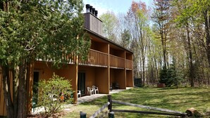A two-story building with a balcony, surrounded by trees and a grassy lawn. - Rib Mountain Inn (Wausau)