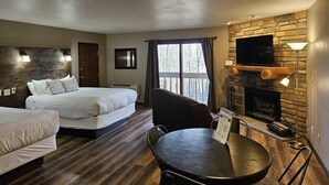 A hotel room with a bed, a desk, a chair, a fireplace, and a TV. - Rib Mountain Inn (Wausau)