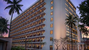 A multi-story hotel with balconies, palm trees, and a sunset sky. - Sokha Beach Resort (Sihanoukville)