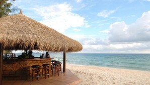 A beach bar with a thatched roof, wooden stools, and a view of the ocean. - Sokha Beach Resort (Sihanoukville)