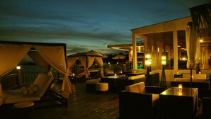 An outdoor lounge area with cushioned seating and umbrellas, overlooking a body of water. - Sokha Beach Resort (Sihanoukville)