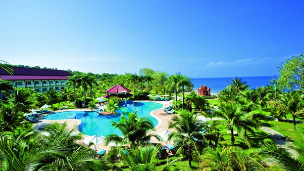 A resort with a large swimming pool, palm trees, and a view of the ocean. - Sokha Beach Resort (Sihanoukville)