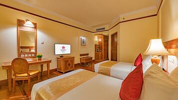 A hotel room with two beds, a desk, a chair, a television, and a wardrobe.