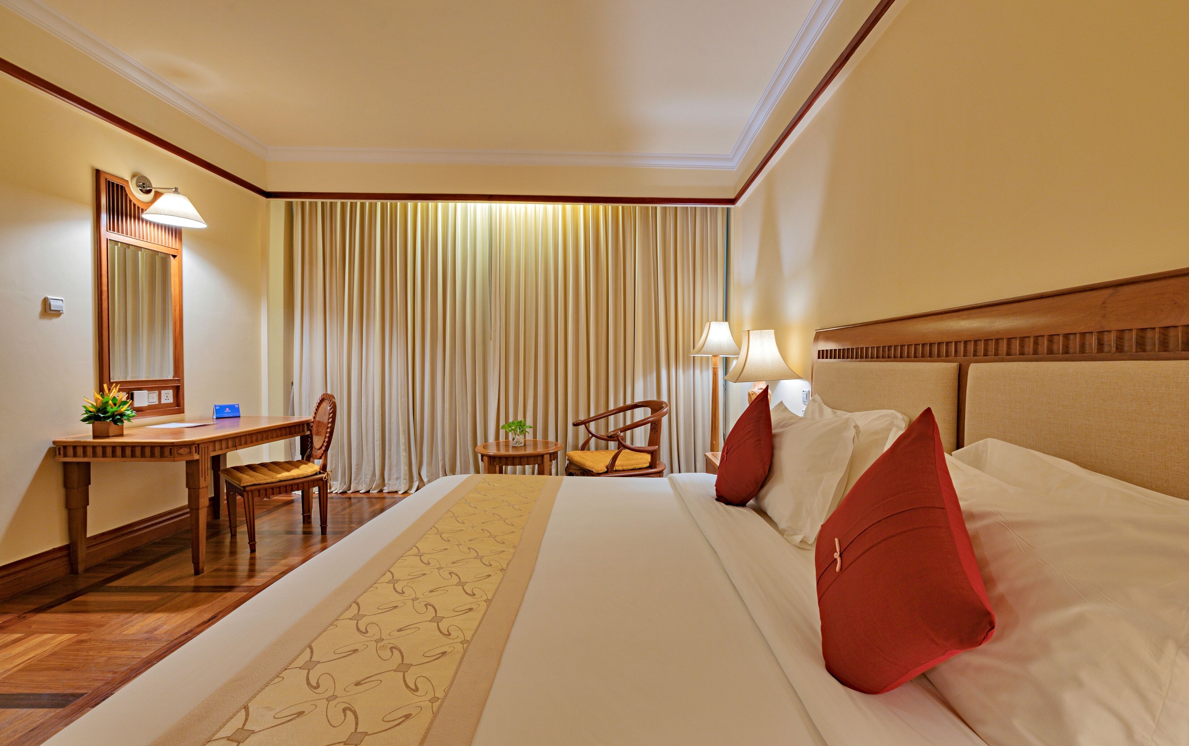 Una habitación de hotel con una cama grande, un escritorio, una silla y una mesita con una planta.