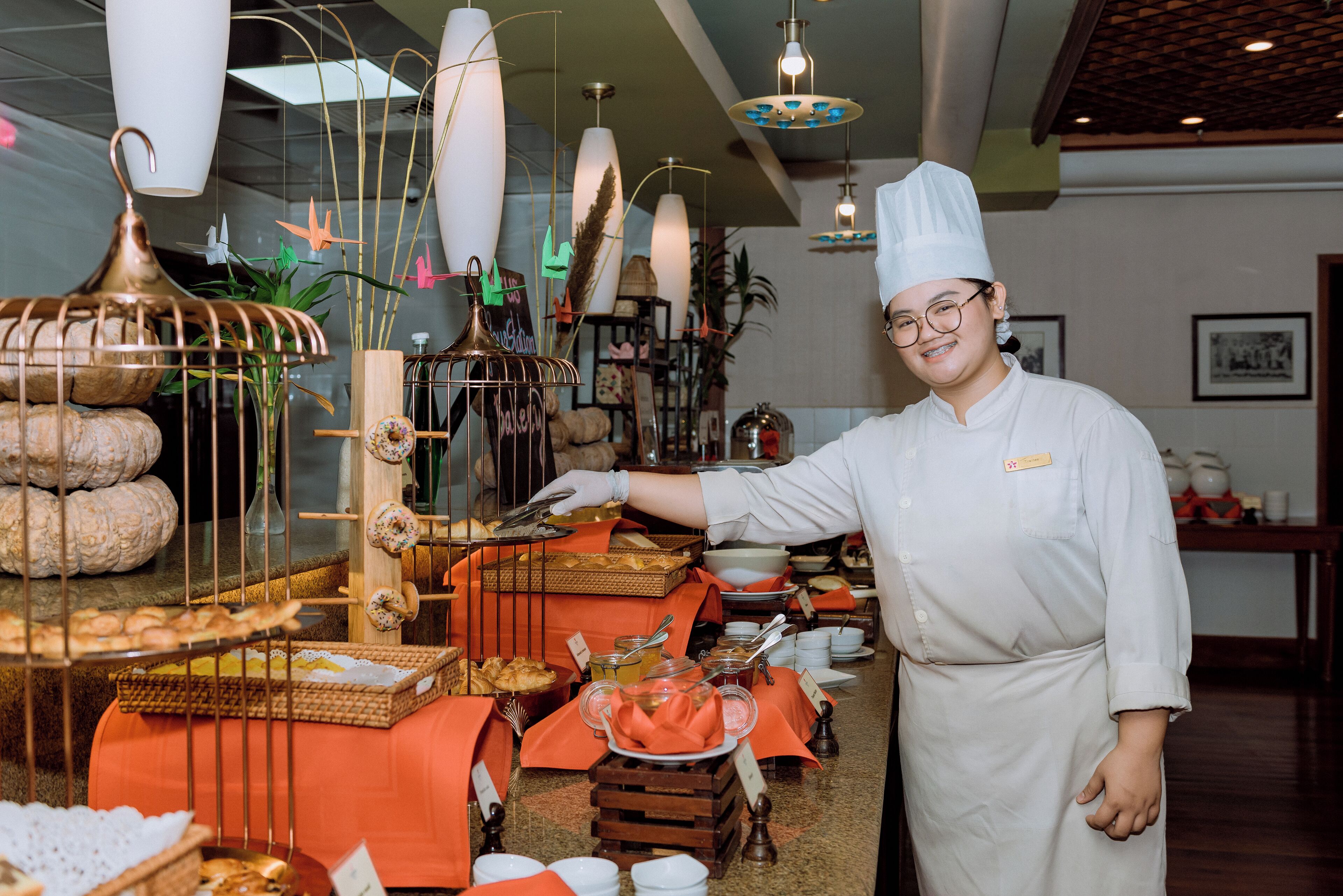 A buffet setup with various food items and a person in chef attire.