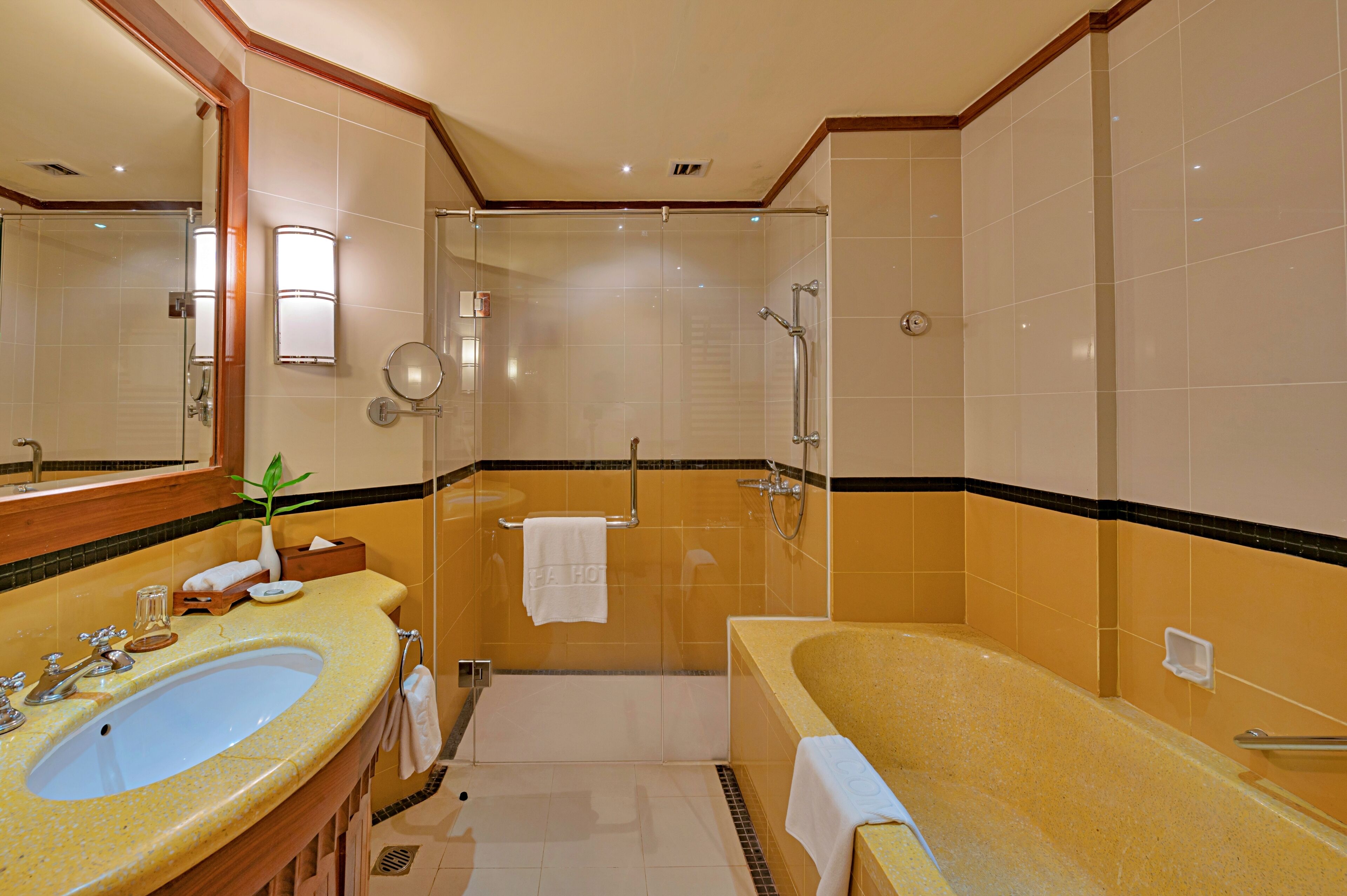 A hotel bathroom with a large sink, a bathtub, a shower area, and a mirror.