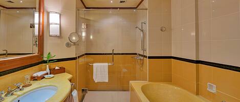 A hotel bathroom with a large sink, a bathtub, a shower area, and a mirror.