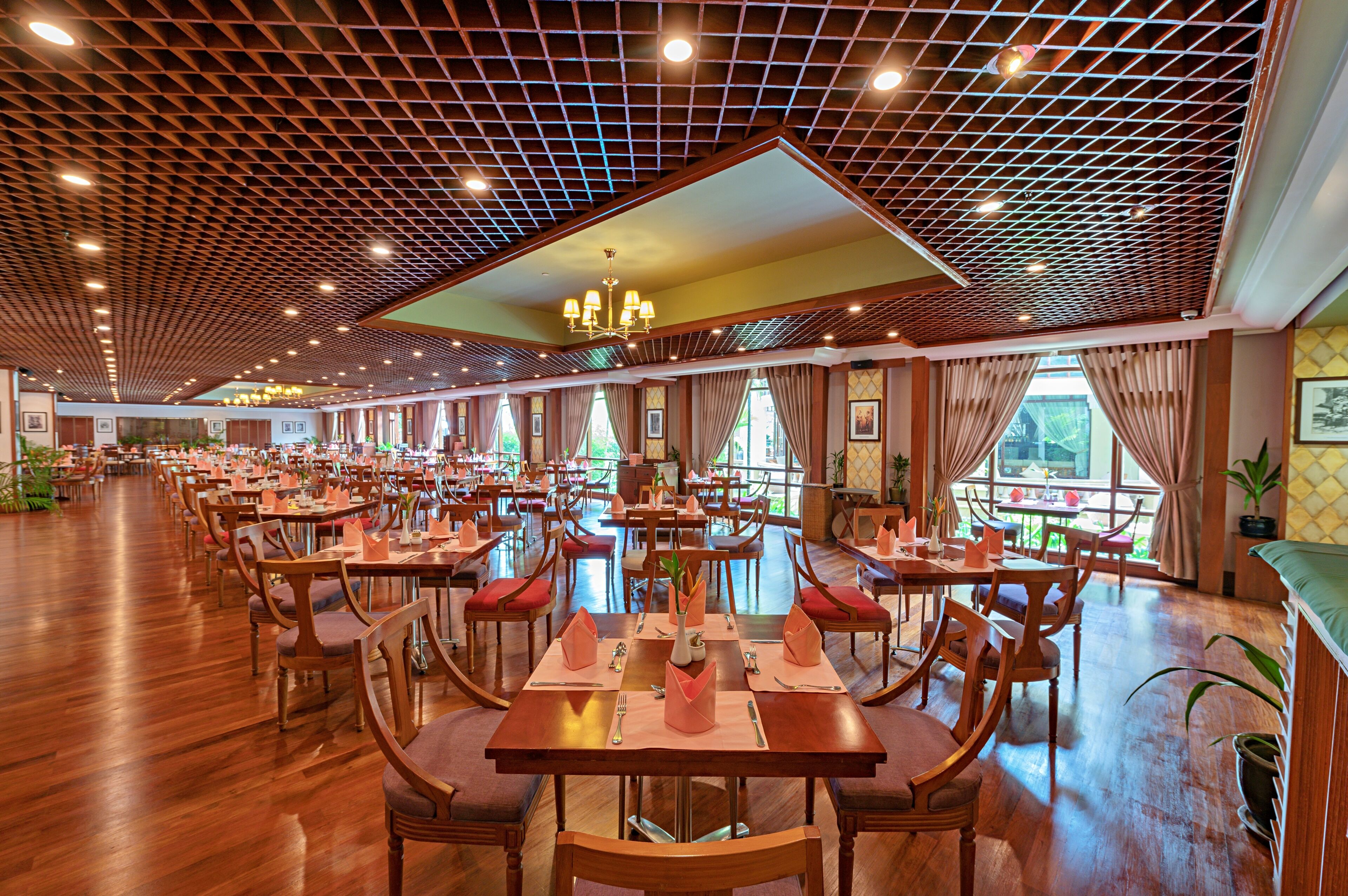 A spacious restaurant with wooden flooring, multiple dining tables, and chairs.