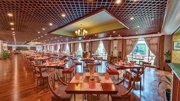 A spacious restaurant with wooden flooring, multiple dining tables, and chairs.