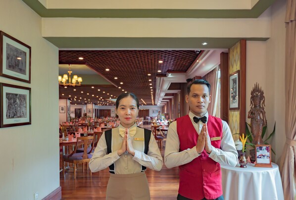 A restaurant interior with a high ceiling, chandeliers, and framed pictures on the walls.