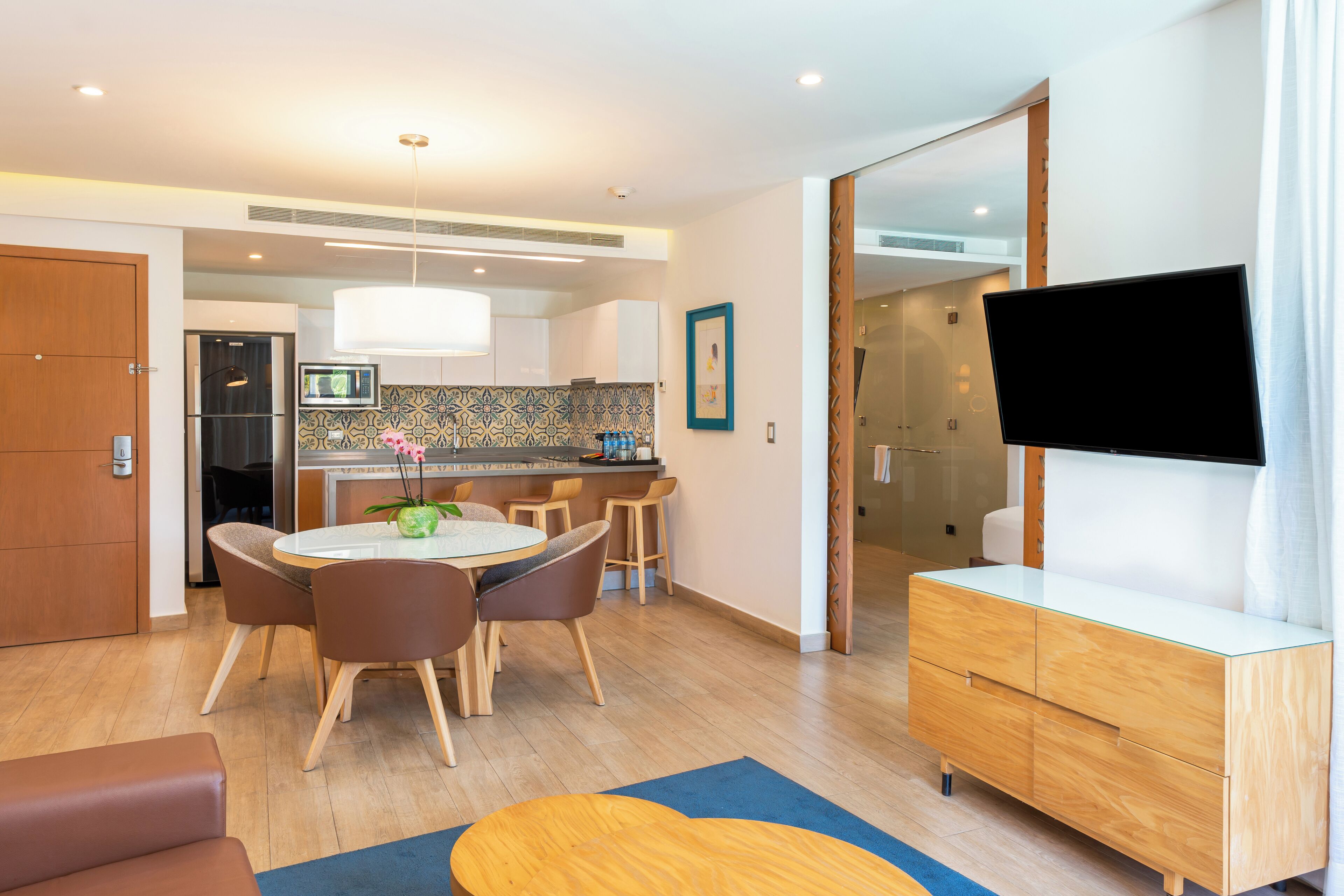 A modern living room with a dining area, a kitchen, and a TV.