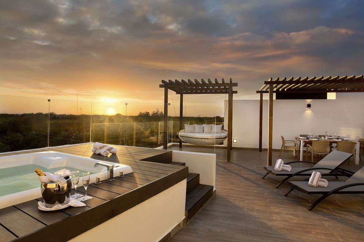 A rooftop terrace with a hot tub, lounge chairs, and a dining area.