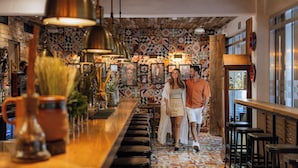 A bar area with a patterned floor, wooden bar counter, and hanging pendant lights. - The Fives Beach Hotel - Á la Carte All Inclusive (Playa del Carmen)