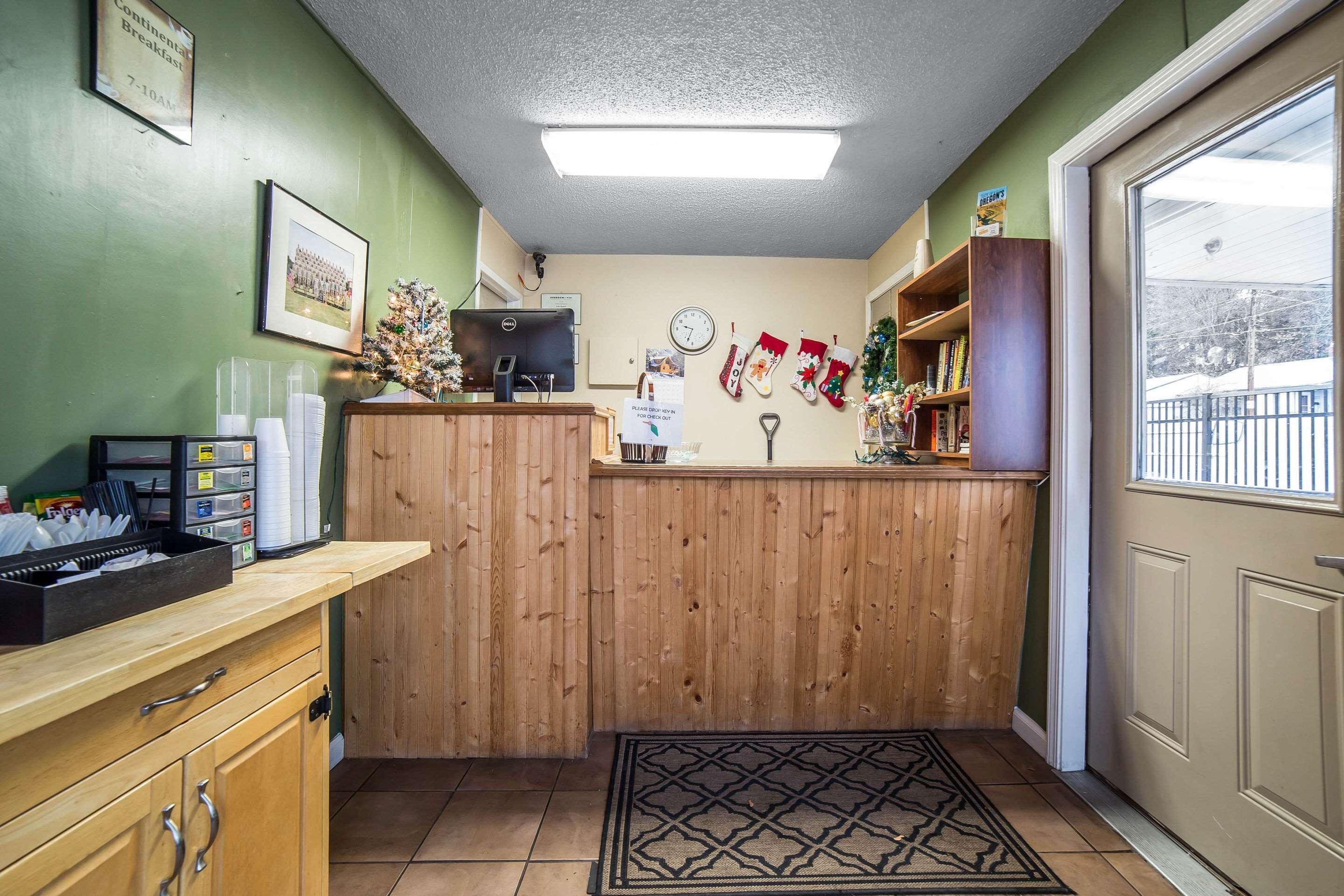 A reception area with a wooden counter, a computer, a clock, and Christmas stockings on the wall.